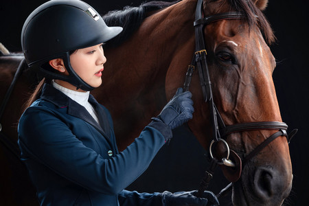 运动人物特写黑色摄影照片_穿女骑装的年轻女子和马