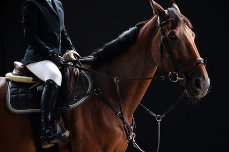 运动人物特写黑色摄影照片_帅气的骑马女孩部分特写