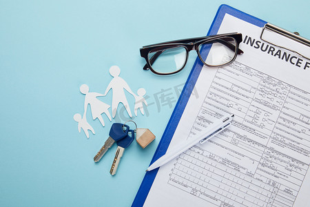 保险形式, 笔, 剪纸家庭和钥匙的顶部看法在蓝色被隔绝的  