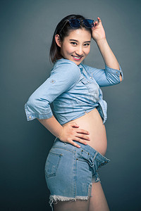 蓝色背景人物图摄影照片_穿着时尚的孕妇
