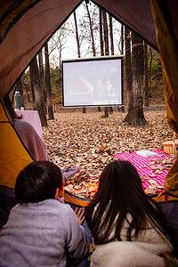 电影活动摄影照片_户外露营的儿童趴在帐篷里看电影