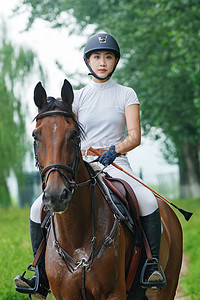 马靴摄影照片_户外骑马的年轻女孩