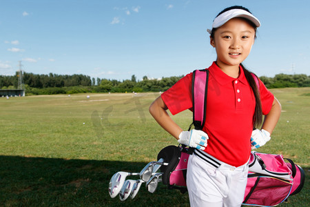 高尔夫球包摄影照片_户外快乐儿童背着高尔夫球包