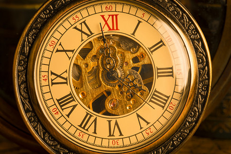 古董书籍摄影照片_以复古书籍为背景的古董时钟。链条上的机械钟表.