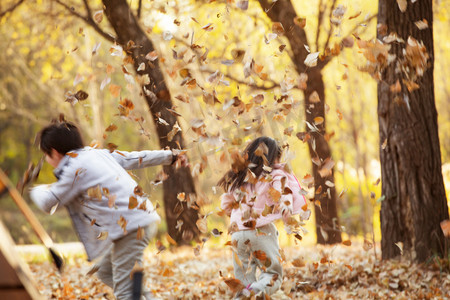 树叶可爱摄影照片_可爱的男孩女孩在户外玩耍背影