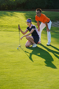 球场上教练指导青年女人打高尔夫