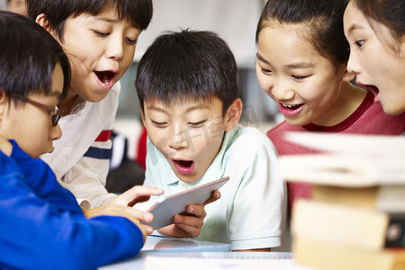 集团的亚洲小学学生玩游戏使用平板电脑