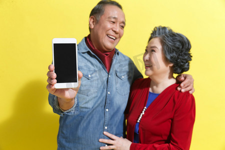 老年人拍照背景图摄影照片_老年夫妇展示手机