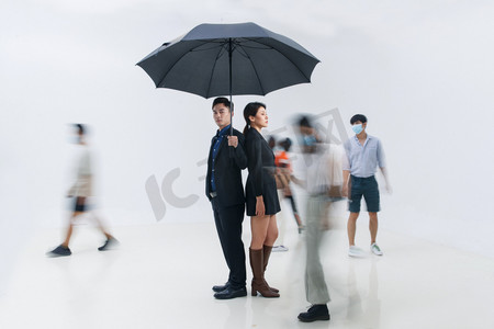 情人节摄影照片_拿着雨伞的商务男女站在人群中