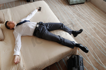 酒店睡觉的人摄影照片_青年男士躺在床上睡觉