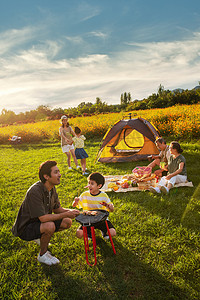 家庭露营摄影照片_欢乐的一家人在郊外野餐烧烤