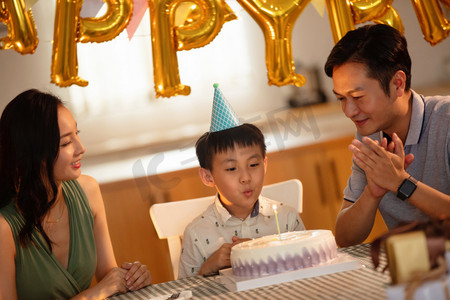 生日许愿摄影照片_欢乐的一家三口庆祝生日