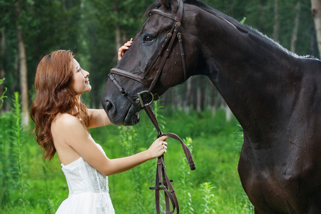 风景骏马摄影照片_漂亮的青年女人抚摸骏马