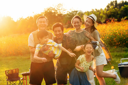 米黄色自然风景摄影照片_站着花丛中的快乐一家人