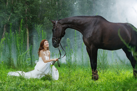 不平滑摄影照片_草地上漂亮的青年女人和马