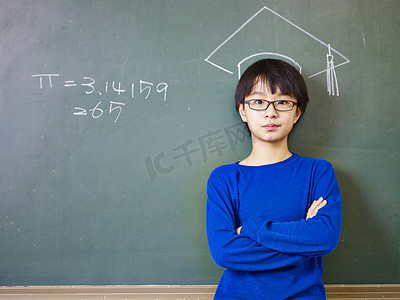 站在粉笔绘制的博士帽下的亚洲小学男生