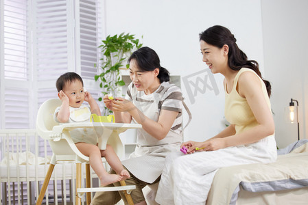 母子吃饭摄影照片_月嫂和年轻妈妈一起喂宝宝吃饭