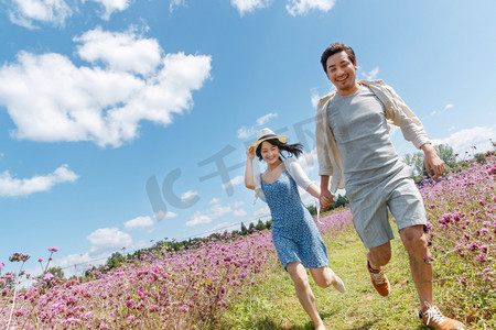 青年夫妇手牵手在花海里奔跑