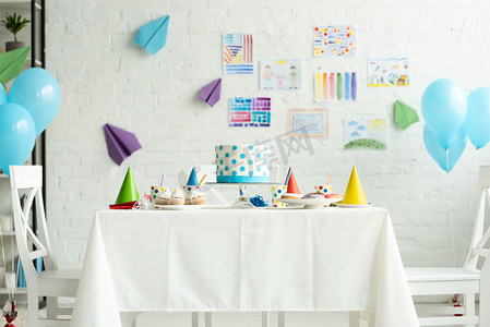 气球礼箱摄影照片_节日蛋糕和党帽在房间里装饰与气球生日派对