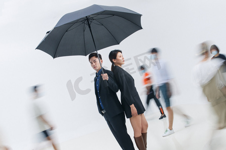 白领摄影照片_拿着雨伞的商务男女站在人群中