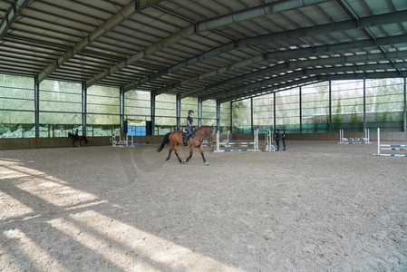 障碍训练场上骑马的青年女人