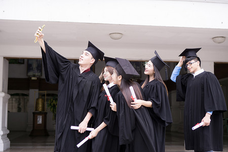 毕业摄影照片_一群成功的同学一起祝贺, 一起扔在空中的毕业帽和庆祝。教育理念.