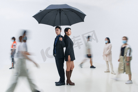 拿着雨伞的商务男女站在人群中