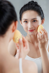 镜子照镜子摄影照片_年轻女人对着镜子化妆