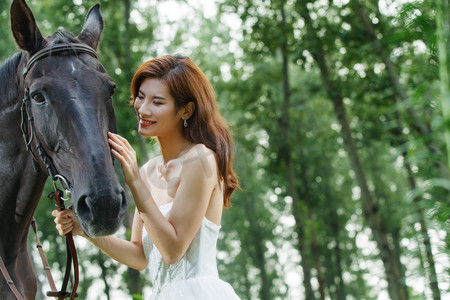 亲昵摄影照片_漂亮的年轻女人亲昵的抚摸着马