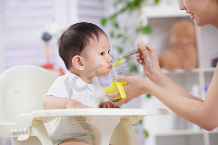 母子吃饭摄影照片_年轻妈妈喂宝宝吃饭