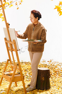 院子里的落叶摄影照片_中老年女人在庭院里画画