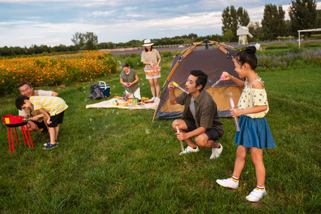 在郊外野餐烧烤青年男女在户外露营欢乐家庭在郊外野炊野餐用品组合毯