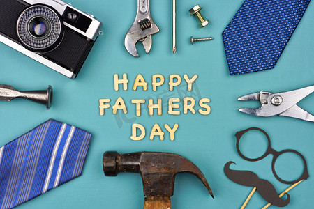 快乐的父亲节消息与框架的礼物, 装饰, 领带和工具在一个蓝色的背景。顶部视图.