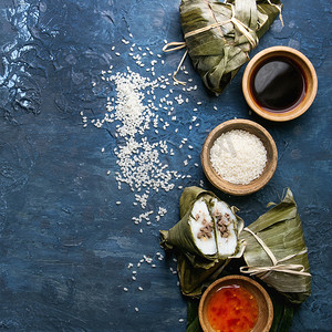 亚洲大米 piramidal 用大米木薯粉和香蕉叶中的肉馅来蒸饺子。以上的成分和调味汁以上的蓝色纹理背景。顶部视图, 空间。方形图像