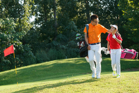 高尔夫上杆摄影照片_球场上教练和学生背着高尔夫球包行走