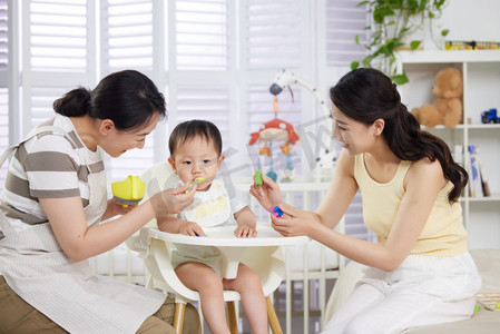 月嫂和年轻妈妈一起喂宝宝吃饭