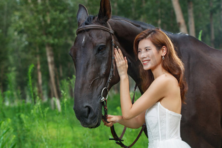 亲昵摄影照片_快乐的年轻女人亲昵的抚摸着马