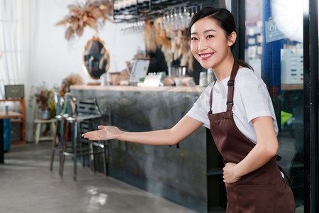 顾客服务摄影照片_咖啡店门口迎接顾客的女服务员