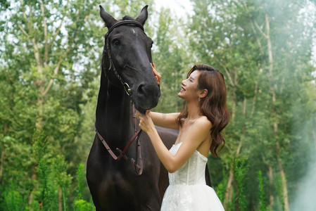 亲昵摄影照片_漂亮的年轻女人亲昵的抚摸着马