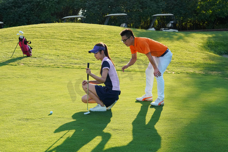 球场上教练指导青年女人打高尔夫