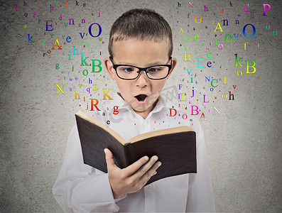 child with glasses reading book