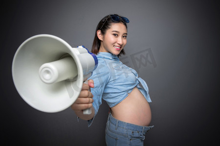 穿着时尚的孕妇拿着扩音器