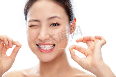 老人用牙线剔牙摄影照片_拿着牙线剔牙的青年女人