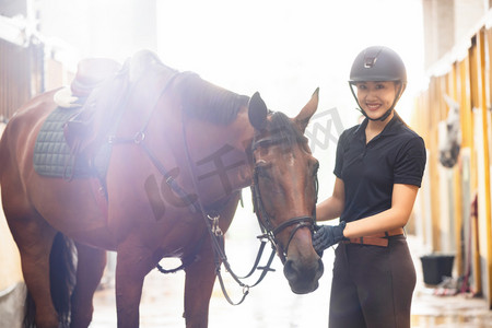 女子骑马摄影照片_马厩里漂亮的年轻女子和马