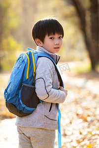 树林小清新摄影照片_秋天户外小路上背书包的小男孩