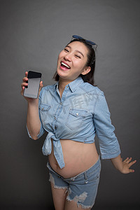 穿着时尚的孕妇拿着手机