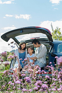 劳动节快乐字体摄影照片_坐在汽车后备箱里玩耍的快乐家庭