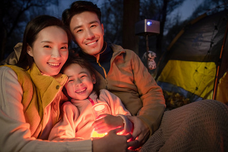 幸福的一家三口夜晚在野外露营