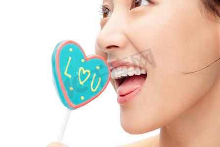 爱心表情摄影照片_拿着心型棒棒糖的青年女人