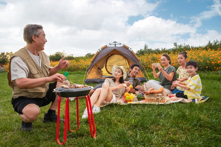 烧烤男孩摄影照片_快乐家庭在郊外烧烤野餐